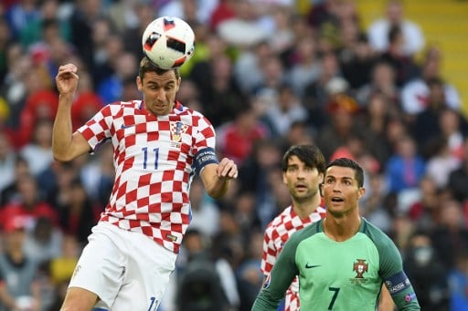 Kroatiens Darijo Srna beim Kopfball,  Portugal's Stürmer Cristiano Ronaldo schaut zu - der neue Spielball der EM Fracas. / AFP PHOTO / FRANCISCO LEONG