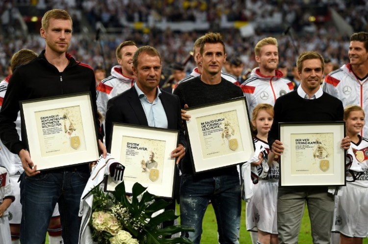 (v. l. n. r.) Der deutsche Verteidiger Per Mertesacker, der deutsche Co-Trainer Hansi Flick, der deutsche Stürmer Miroslav Klose und der deutsche Mittelfeldspieler Philipp Lahm posieren mit ihrer Auszeichnung für ein Foto, nachdem sie vor dem Freundschaftsspiel zwischen Deutschland und Argentinien am 3. September 2014 in Düsseldorf offiziell aus der deutschen Nationalmannschaft zurückgetreten sind. AFP PHOTO / PATRIK STOLLARZ