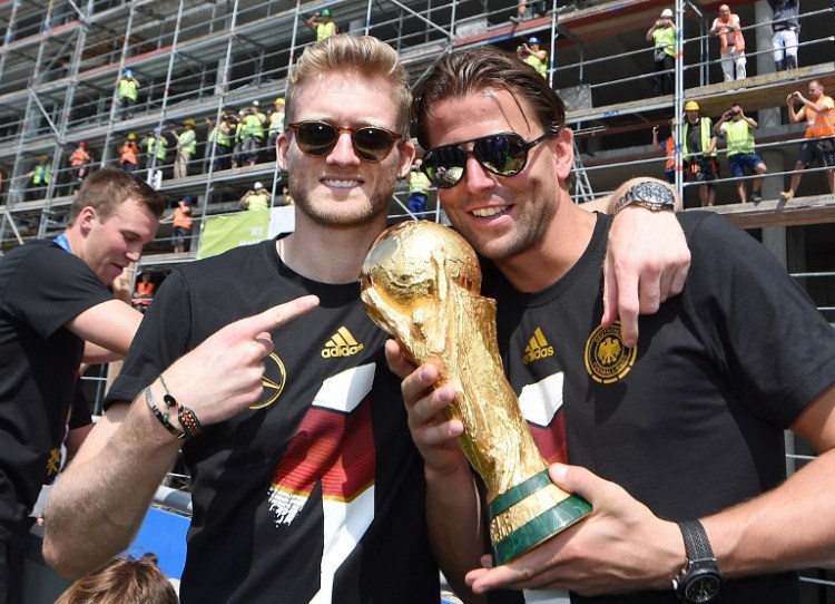 Andre Schuerrle und Roman Weidenfeller posieren mit dem Weltpokal nach dem Gewinn der Weltmeisterschaft bei der Rückkehr in Berlin.