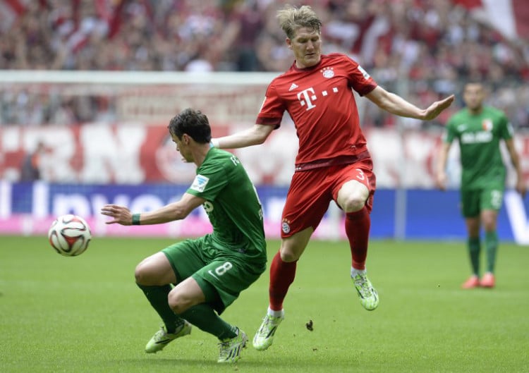 Bastian Schweinsteiger (R) im neuen roten Bayerntrikot und Augsburg's Mittelfeldspieler Markus Feulner (L) beim Bundesliga Spiel zwischen dem FC Bayern und dem FC Augsburg in München. AFP PHOTO / CHRISTOF STACHE