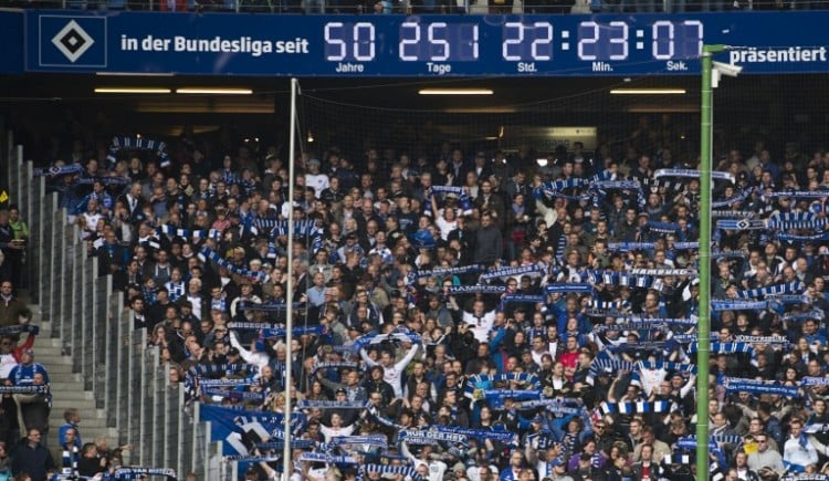 Hamburger Fußballfans im Volksparkstadion unter der berühmten Uhr "Hamburg, in der Bundesliga seit 50 Jahren und 251 Tagen vor dem Bundesliga-Spiel Hamburger SV gegen den FC Bayern München am 3.Mai 2014. AFP PHOTO / JOHN MACDOUGALL