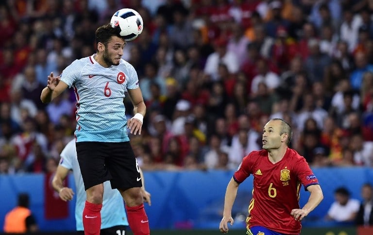 Turkey's midfielder Hakan Calhanoglu (L) heads the ball as Spain's midfielder Andres Iniesta runs past during the Euro 2016 group D football match between Spain and Turkey at the Allianz Riviera stadium in Nice on June 17, 2016.  / AFP PHOTO / TOBIAS SCHWARZ