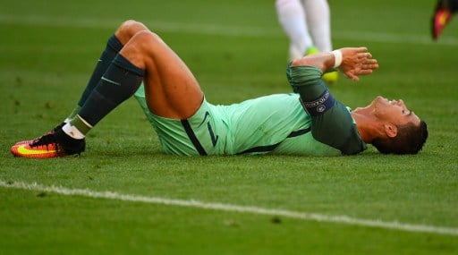 Portugal's forward Cristiano Ronaldo reacts on the ground during the Euro 2016 group F football match between Hungary and Portugal at the Parc Olympique Lyonnais stadium in Decines-Charpieu, near Lyon, on June 22, 2016. / AFP PHOTO / Joe KLAMAR