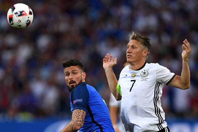 Frankreichs Olivier Giroud im Zweikampf mit Bastian Schweinsteiger. / AFP PHOTO / PATRIK STOLLARZ