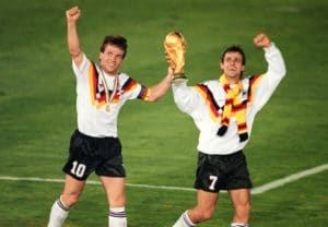 Mittelfeldspieler Lothar Matthäus (l.) und der Stürmer Pierre Littbarski feiern mit der WM-Trophäe, nachdem ihre Mannschaft den Titelverteidiger - Argentinien - im WM-Finale am 08. Juli 1990 in Rom durch einen Elfmeter von Verteidiger Andreas Brehme mit 1:0 besiegt hat. Es ist der dritte Weltmeistertitel für Deutschland (1954, 1974 und 1990). AFP-FOTO
