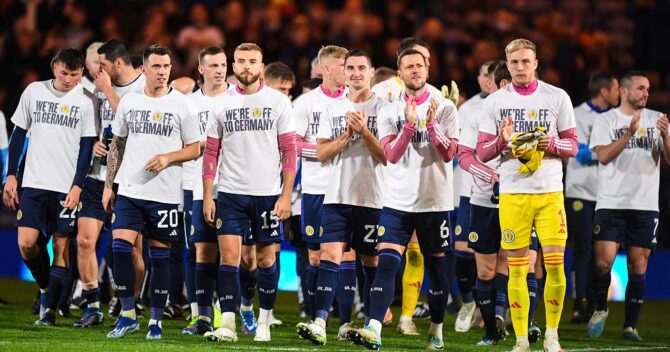 Die Spieler der schottischen Mannschaft jubeln nach dem UEFA-Euro-2024-Qualifikationsspiel der Gruppe A zwischen Schottland und Norwegen im Hampden Park Stadion in Glasgow am 19. November 2023 mit einem T-Shirt mit der Aufschrift "Wir fahren nach Deutschland". - Schottland schaffte den Ausgleich zum 3:3 gegen Norwegen und ist damit für die Euro 2024 qualifiziert. (Foto: ANDY BUCHANAN / AFP)