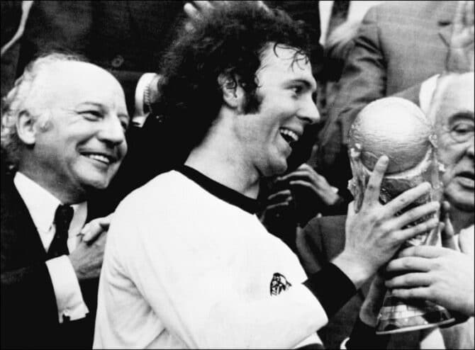 Kapitän Franz Beckenbauer erhält WM-Pokal nach dem 2:1 Sieg gegen Holland am 07. Juli 1974 . Deutschlands damaliger Bundespräsident Walter Scheel (L) applaudiert. (Foto AFP)
