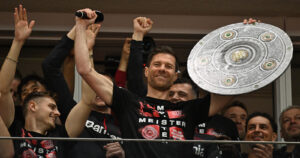 Bayer Leverkusens spanischer Cheftrainer Xabi Alonso feiert mit einer Attrappe des Bundesligapokals mit seinen Spielern nach dem Bundesligaspiel Bayer 04 Leverkusen gegen Werder Bremen in Leverkusen, Westdeutschland, am 14. April 2024. - Bayer Leverkusen wurde am 14. April 2024 zum ersten Mal Meister der Bundesliga 2023-24. (Photo by INA FASSBENDER / AFP)AND/OR QUASI-VIDEO