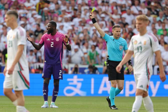 Der deutsche Verteidiger Antonio Rüdiger (Nr. 02) holt sich vom niederländischen Schiedsrichter Danny Makkelie eine Gelbe KArte ab. Bei der 2.wäre er gesperrt für das Achtelfinale. (Foto: LLUIS GENE / AFP)