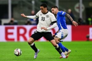 Im neuen 125 Jahre DFB Trikot: Der deutsche Mittelfeldspieler Jamal Musiala (Nr. 10) kämpft mit dem italienischen Stürmer Matteo Politano (Nr. 07) während des Viertelfinal-Hinspiels der Nations League zwischen Italien und Deutschland am 20. März 2025 im San-Siro-Stadion in Mailand um den Ball. (Foto: Marco BERTORELLO / AFP)