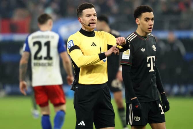 Schiedsrichter Harm Osmers (links) neben Jamal Musiala (Nr. 10) vom FC Bayern München während des Fußballspiels der deutschen Bundesliga zwischen dem Hamburger SV und dem FC Bayern München in Hamburg am 31. Januar 2026. (Foto: IBRAHIM OT / AFP)
