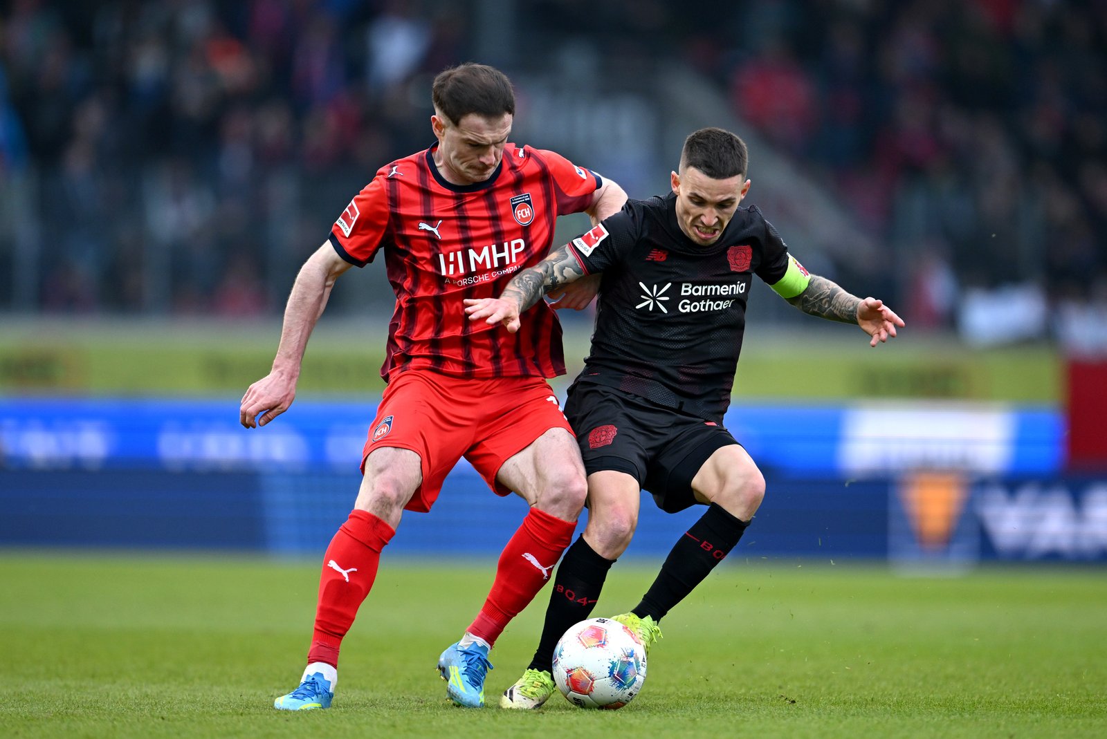 Alex Grimaldo von Bayer 04 Leverkusen im Zweikampf mit Budu Zivzivadze von 1. FC Heidenheim 1846 im Bundesliga-Spiel in der Voith-Arena am 21. März 2026. Christian Kaspar-Bartke / Getty Images