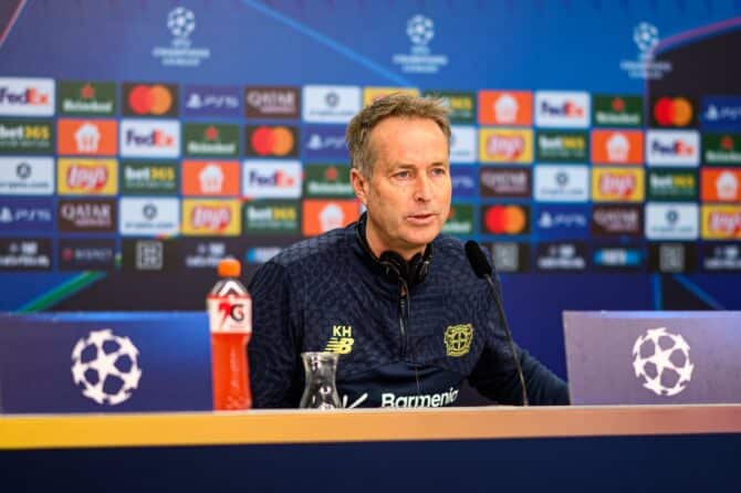 LEVERKUSEN, 10. MÄRZ 2026: Kasper Hjulmand, Cheftrainer von Bayer 04 Leverkusen, spricht auf der Pressekonferenz vor dem UEFA-Champions-League-Achtelfinale gegen den FC Arsenal. Der dänische Coach sitzt vor der offiziellen Sponsorenwand der Champions League am Mikrofon und trägt den dunkelblauen Trainingsanzug der Werkself. (Copyright Depositphotos.com)