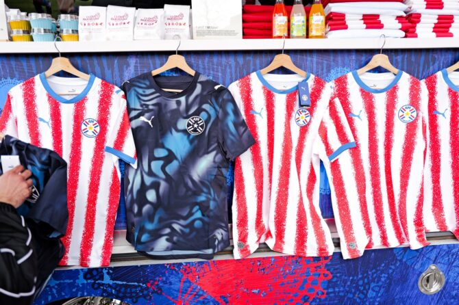 Die neuen Puma-Trikots der paraguayischen Nationalmannschaft, präsentiert beim WM-2026-Launch-Event in New York am 19. März 2026. Im Vordergrund hängt das Heimtrikot in Rot-Weiß sowie das dunkelblaue Auswärtstrikot. (Copyright Puma)