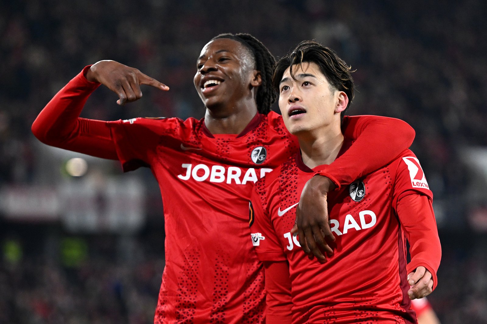 Yuito Suzuki vom SC Freiburg bejubelt gemeinsam mit Johan Manzambi seinen Treffer zum 4:0 im UEFA-Europa-League-Achtelfinale (Rückspiel) gegen KRC Genk im Stadion am Wolfswinkel in Freiburg im Breisgau am 19. März 2026. Christian Kaspar-Bartke / Getty Images Europe via Getty Images