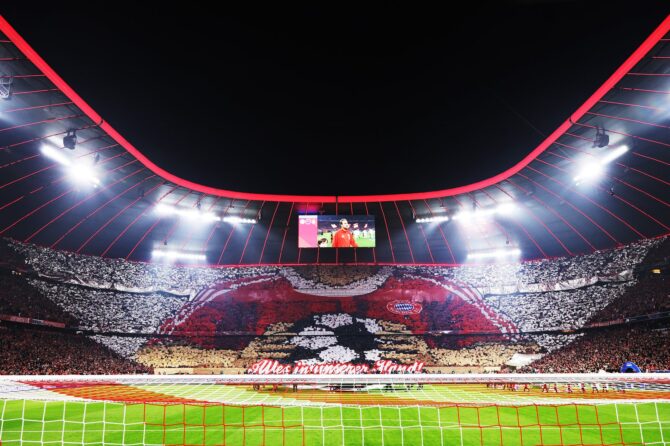 Die Südkurve der Allianz Arena präsentiert beim Champions-League-Viertelfinale-Rückspiel gegen Real Madrid im April 2026 eine spektakuläre Fankoreografie mit dem FC-Bayern-Logo – die vollbesetzte Arena strahlt in rotem Licht. (Getty Images)