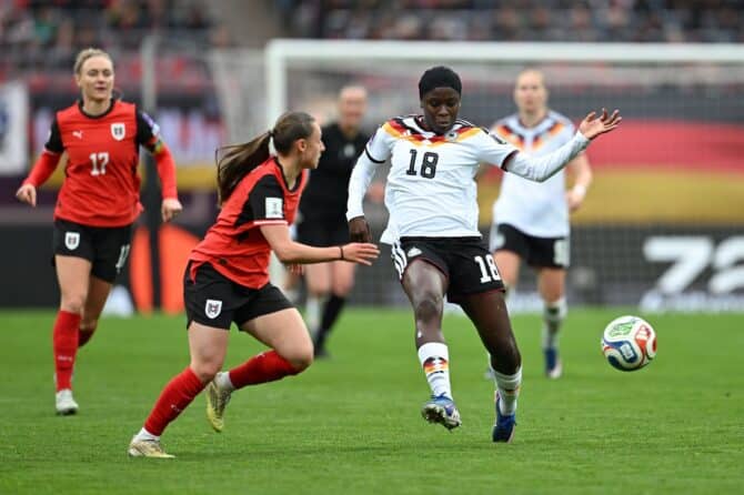 Nicole Anyomi (Nr. 18) von der deutschen Frauen-Nationalmannschaft setzt sich im WM-Qualifikationsspiel gegen Österreich durch und spielt den Ball, während Chiara D'Angelo von Österreich sie unter Druck setzt. Das Spiel fand am 14. April 2026 im Max-Morlock-Stadion in Nürnberg statt. Christian Kaspar-Bartke / Getty Images
