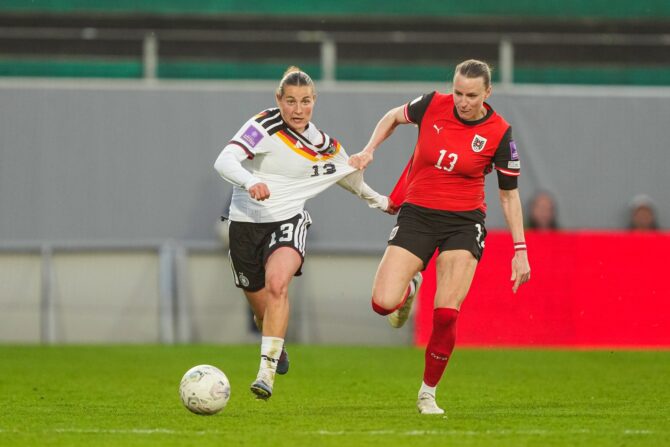 Nicole Anyomi (Nr. 13) setzt sich im WM-Qualifikations-Auswärtsspiel bei Österreich 2026 durch – die österreichische Gegenspielerin (ebenfalls Nr. 13) greift dabei regelwidrig ins Trikot der deutschen Angreiferin. (Getty Images)