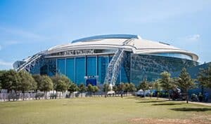 Das AT&T Stadium in Arlington bei Dallas aus der Außenperspektive – die imposante Heimstätte der Dallas Cowboys mit ihrer markanten Glashülle und dem Bogendach ist einer der Austragungsorte der FIFA Fußball-Weltmeisterschaft 2026 in den USA. (Copyright Depositphotos.com)