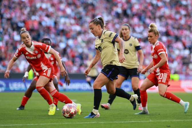 Barcelona-Spielerin dribbelt mit dem Ball gegen zwei Bayern München Spielerinnen im Frauen Champions League Halbfinale. Intensives Spielgeschehen in der Allianz Arena. Getty Images