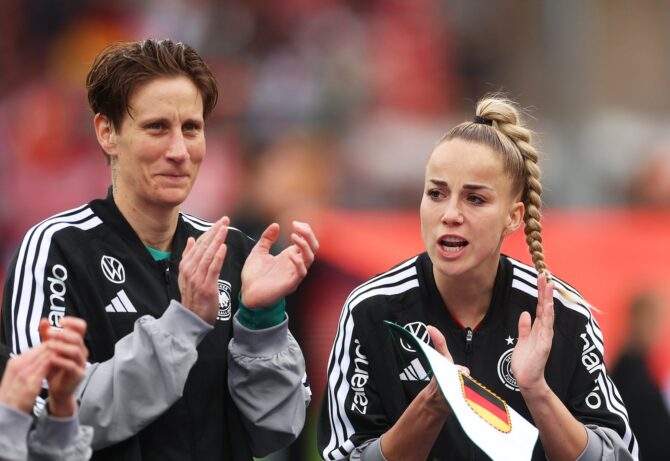 Zwei Spielerinnen der deutschen Frauen-Nationalmannschaft applaudieren emotional nach dem WM-Qualifikationsspiel gegen Österreich 2026 – eine von ihnen hält einen DFB-Wimpel als Erinnerung an ein besonderes Spiel in den Händen. (Getty Images)