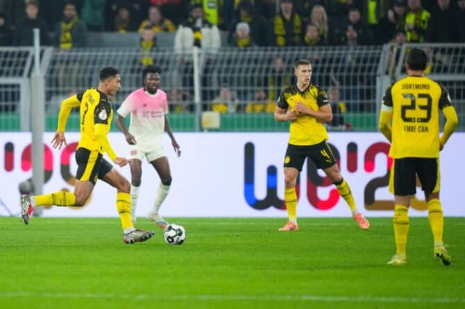 Borussia Dortmund im DFB-Pokal-Achtelfinale gegen Bayer 04 Leverkusen am 2. Dezember 2025 im Signal Iduna Park – BVB-Kapitän Emre Can (Nr. 23, rechts) und Nico Schlotterbeck (Nr. 4, Mitte) verfolgen das Spielgeschehen, während ein Mitspieler im Vordergrund den Ball scharf aufs Tor bringt. Pau Barrena / Getty Images