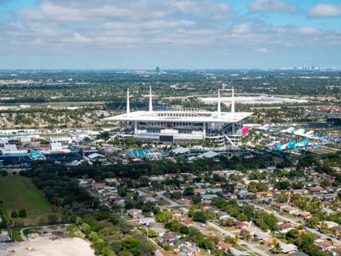Luftaufnahme des Hard Rock Stadium in Miami Gardens, Florida – Austragungsort der FIFA Fußball-Weltmeisterschaft 2026. Die Drohnenaufnahme zeigt das Stadion mit seinem markanten weißen Zeltdach inmitten des Stadtgebiets, aufgenommen anlässlich des Super Bowl LIV. In der Ferne ist die Skyline von Miami zu erkennen. (Copyright Depositphotos.com)