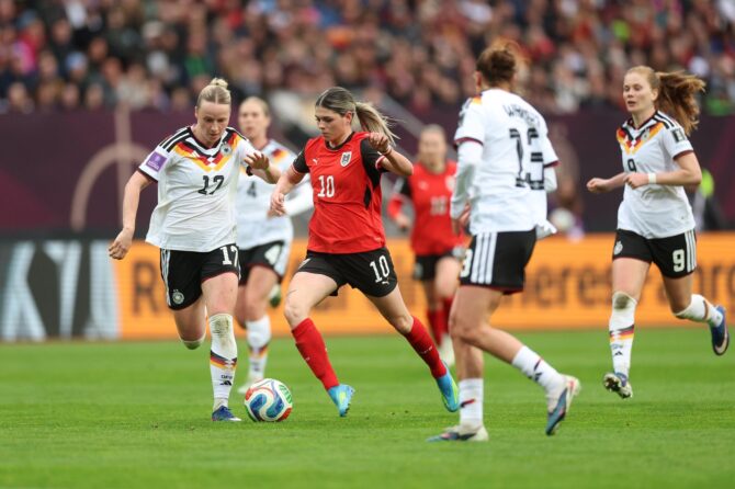Franziska Kett (Nr. 17) von Deutschland fordert Eileen Campbell (Nr. 10) von Österreich heraus beim WM-Qualifikationsspiel am 14. April 2026 im Max-Morlock-Stadion in Nürnberg. Die österreichische Mittelfeldspielerin behauptet sich im Zweikampf, während weitere deutsche Spielerinnen die Szene einrahmen. Adam Pretty / Getty Images