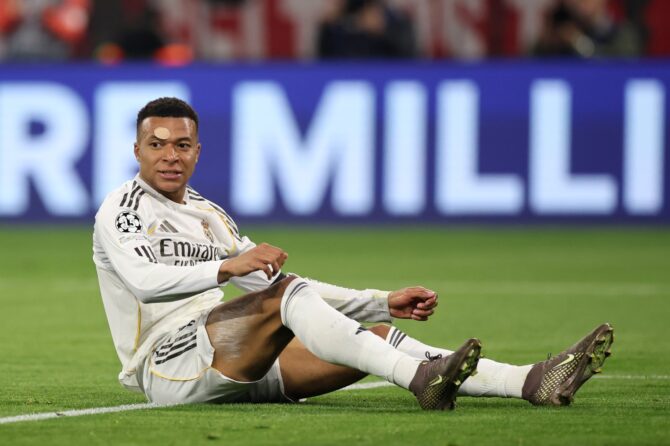 Kylian Mbappé sitzt auf dem Rasen der Football Arena München und reagiert auf eine Spielszene im UEFA Champions League Viertelfinale-Rückspiel zwischen dem FC Bayern München und Real Madrid CF am 15. April 2026. Alex Grimm / Getty Images
