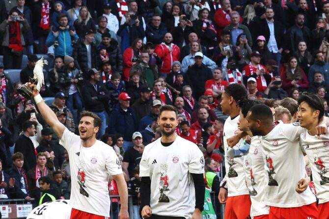 Leon Goretzka (#8) vom FC Bayern München hält die legendäre Kakadu-Porzellanfigur in die Höhe, während das Team die Bundesliga-Meisterschaft nach dem Sieg gegen den VfB Stuttgart in der Allianz Arena in München am 19. April 2026 feiert. (Copyright AFP/Karl-Josef Hildenbrand)