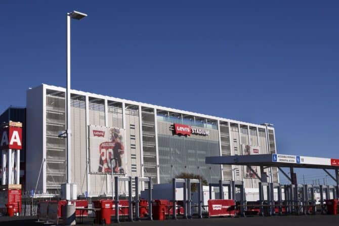 Außenansicht des Levi's Stadium in Santa Clara, Heimstadion der San Francisco 49ers aus der NFL. Das moderne Stadion in der San Francisco Bay Area ist Austragungsort der FIFA Fußball-Weltmeisterschaft 2026. Die Aufnahme zeigt den Eingangsbereich mit den charakteristischen Drehtüren und einem großformatigen Spieler-Wandbild an der Fassade. (Copyright Depositphotos.com)