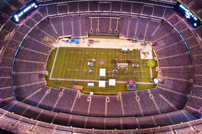 Vogelperspektive auf das Innere des MetLife Stadium in East Rutherford, New Jersey. Die Luftaufnahme zeigt das ovale Stadion von oben mit dem beleuchteten Spielfeld und den vollbesetzten Rängen. Das MetLife Stadium, Heimstadion der New York Giants und der New York Jets aus der NFL, ist Austragungsort der FIFA Fußball-Weltmeisterschaft 2026. (Copyright Depositphotos.com)