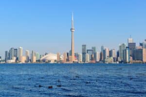 Die Skyline von Toronto spiegelt sich im Lake Ontario – mit dem markanten CN Tower und dem Rogers Centre als Wahrzeichen der kanadischen Metropole, die bei der FIFA Fußball-Weltmeisterschaft 2026 als Gastgeberstadt fungiert. (Copyright Depositphotos.com)