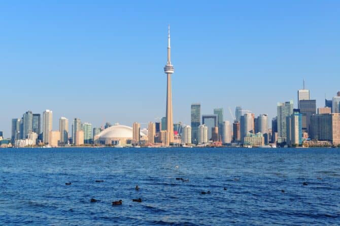 Die Skyline von Toronto spiegelt sich im Lake Ontario – mit dem markanten CN Tower und dem Rogers Centre als Wahrzeichen der kanadischen Metropole, die bei der FIFA Fußball-Weltmeisterschaft 2026 als Gastgeberstadt fungiert. (Copyright Depositphotos.com)
