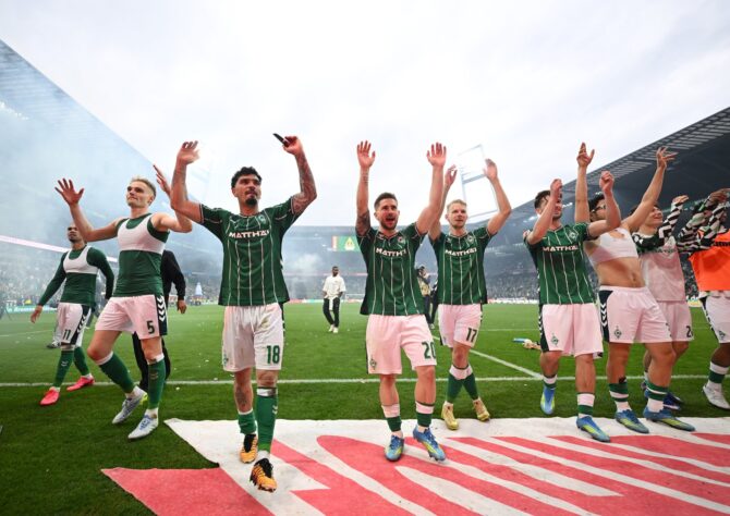 Die Spieler von Werder Bremen feiern mit erhobenen Armen vor der Fankurve nach dem Bundesliga-Derby-Sieg gegen den Hamburger SV 2026 – mit dabei Matthias Ginter (Nr. 18) und weitere Stammspieler des grün-weißen Teams. (Getty Images)