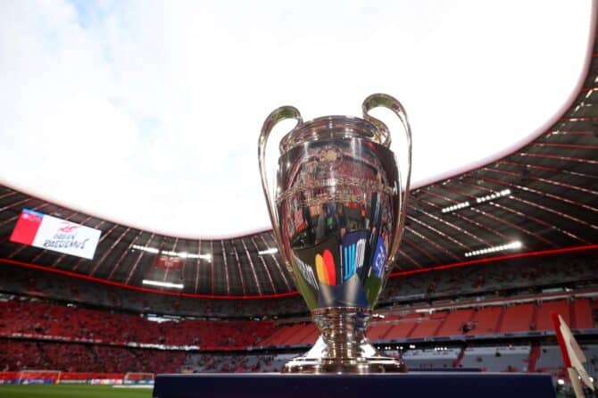 Der UEFA-Champions-League-Pokal steht am 6. Mai 2026 vor dem Anpfiff auf dem Rasen der Allianz Arena in München. Im Hintergrund ist die vollbesetzte Arena zu sehen, in der das Halbfinale-Rückspiel der UEFA Champions League 2025/26 zwischen dem FC Bayern München und Paris Saint-Germain ausgetragen wurde. (Getty Images)