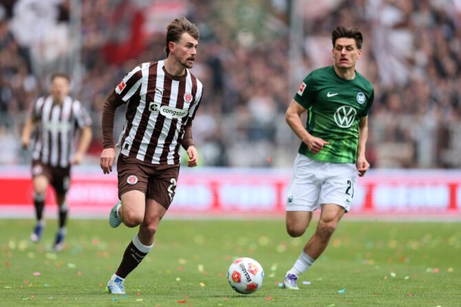 Conor Metcalfe vom FC St. Pauli treibt den Ball nach vorn, bedrängt von Joakim Maehle vom VfL Wolfsburg. Die Szene entstand beim Bundesliga-Spiel zwischen dem FC St. Pauli und dem VfL Wolfsburg im Millerntor-Stadion in Hamburg, Mai 2026. Selim Sudheimer / Getty Images