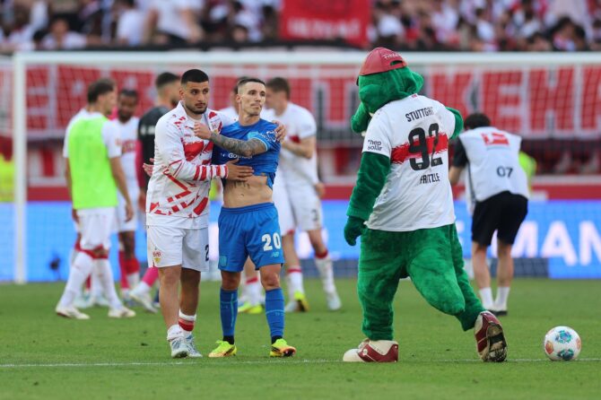 Deniz Undav vom VfB Stuttgart umarmt Alex Grimaldo von Bayer 04 Leverkusen nach dem Bundesliga-Duell in der MHPArena am 9. Mai 2026 in Stuttgart. Im Hintergrund mischt sich Maskottchen Fritzle unter die Spieler. Adam Pretty / Getty Images
