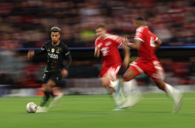 Désiré Doué von Paris Saint-Germain dribbelt am 6. Mai 2026 an zwei FC-Bayern-Verteidigern vorbei. Das dynamische Foto mit Bewegungsunschärfe entstand im Halbfinale-Rückspiel der UEFA Champions League 2025/26 in der Allianz Arena in München. (Getty Images)