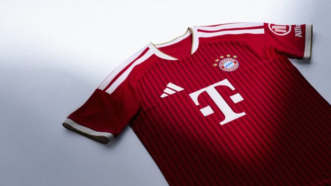 Das neue rote Adidas Heimtrikot des FC Bayern München für die Saison 2026/27 als Produktaufnahme. Das klassische Bayern-Rot mit dem T-Mobile Logo als Hauptsponsor, dem FCB-Vereinswappen und dem Allianz-Badge am Ärmel. (Copyright Adidas)