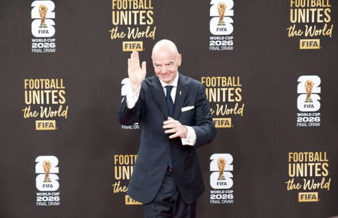 FIFA-Präsident Gianni Infantino winkt beim Final Draw der FIFA Fußball-Weltmeisterschaft 2026 in die Kameras. Im Hintergrund ist das offizielle Motto des Turniers Football Unites the World zu lesen. (Copyright Depositphotos.com)