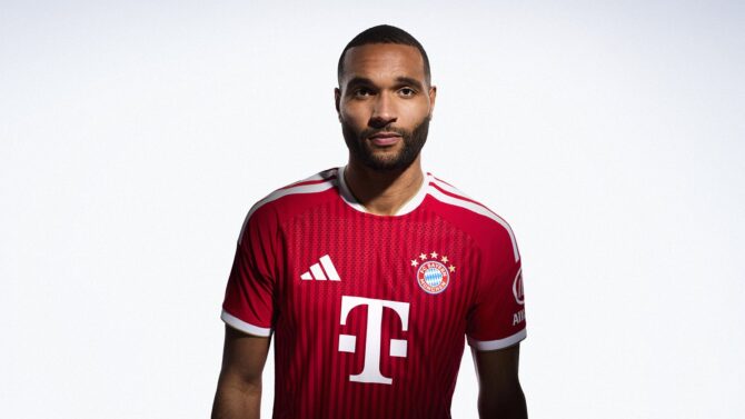 Jonathan Tah vom FC Bayern München präsentiert in Nahaufnahme das neue rote Adidas Heimtrikot der Saison 2026/27. (Copyright Adidas)