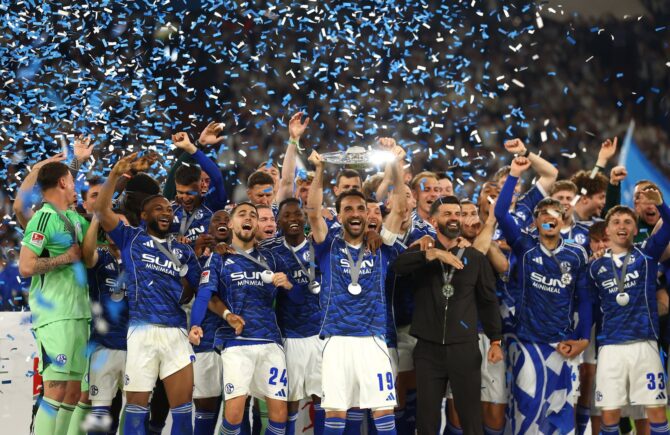 Kenan Karaman reckt nach dem Zweitliga-Heimspiel gegen Eintracht Braunschweig gemeinsam mit seinen Mitspielern die Trophäe der 2. Bundesliga in die Höhe. Der FC Schalke 04 feiert den Titelgewinn unter Konfettiregen in der Veltins-Arena am 17. Mai 2026. Dean Mouhtaropoulos / Getty Images