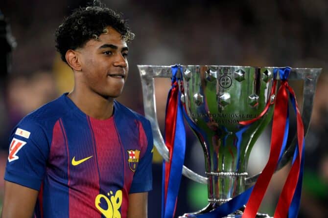 Lamine Yamal von FC Barcelona, der das Spiel verletzungsbedingt verpasste, läuft an der LaLiga-EA-Sports-Trophäe vorbei auf dem Weg zur Siegerehrung, nachdem Barcelona Real Madrid bezwungen und die sp