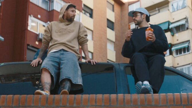 Lionel Messi und Musiker Bad Bunny sitzen entspannt auf einem alten Auto in einem städtischen Hinterhof und unterhalten sich – eine Szene aus dem adidas-Kurzfilm "Backyard Legends", der am 7. Mai 2026 zur Einstimmung auf die FIFA Weltmeisterschaft 2026™ veröffentlicht wurde. (Copyright adidas)