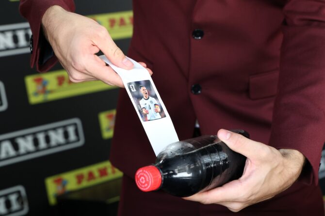 Ein Besucher zieht beim Community-Event der FIFA World Cup Trophy Tour by Coca-Cola am 24. April 2026 in Dallas einen Panini-Sticker aus einer Coca-Cola-Flasche — ein Sonderformat der offiziellen Sticker-Kollektion zur FIFA Weltmeisterschaft 2026. Das Motiv zeigt einen deutschen Nationalspieler. (Rick Kern / Getty Images)