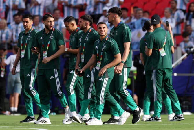 Algerische Nationalspieler in grünen Trainingsanzügen gehen über den Stadionrasen
