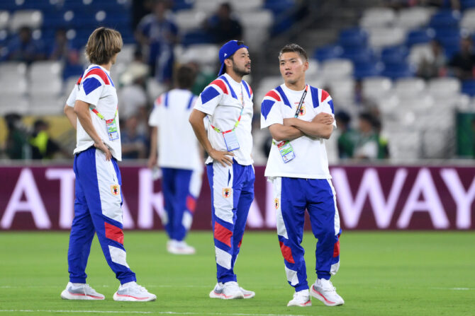 Drei japanische Nationalspieler in weiss-blauer Aufwärmkleidung stehen vor dem Spiel auf dem Rasen des Stadions.