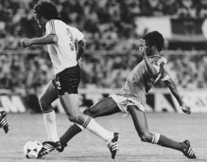 SEVILLA, SPANIEN - 1982: Frankreichs Mittelfeldspieler Jean Tigana (rechts) streckt sich im WM-Halbfinale gegen Westdeutschland nach dem Ball und attackiert Paul Breitner. Die Partie im Estadio Sánchez Pizjuán gilt als eines der dramatischsten Spiele der WM-Geschichte und endete nach Elfmeterschießen mit dem Einzug der Deutschen ins Finale. (Foto: Keystone/Getty Images)