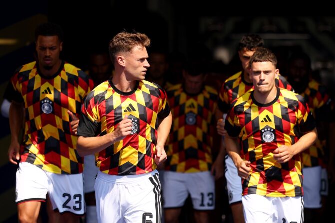 Joshua Kimmich (Nummer 6) führt gemeinsam mit Felix Nmecha (Nummer 23) und Florian Wirtz (Nummer 17) die deutsche Mannschaft im schwarz-rot-goldenen Aufwärmtrikot aus dem Spielertunnel zum Warmmachen. Aufgenommen vor dem Sechzehntelfinale der WM 2026 zwischen Deutschland und Paraguay im Boston Stadium in Foxborough am 29. Juni 2026. (Robert Cianflone / Getty Images)